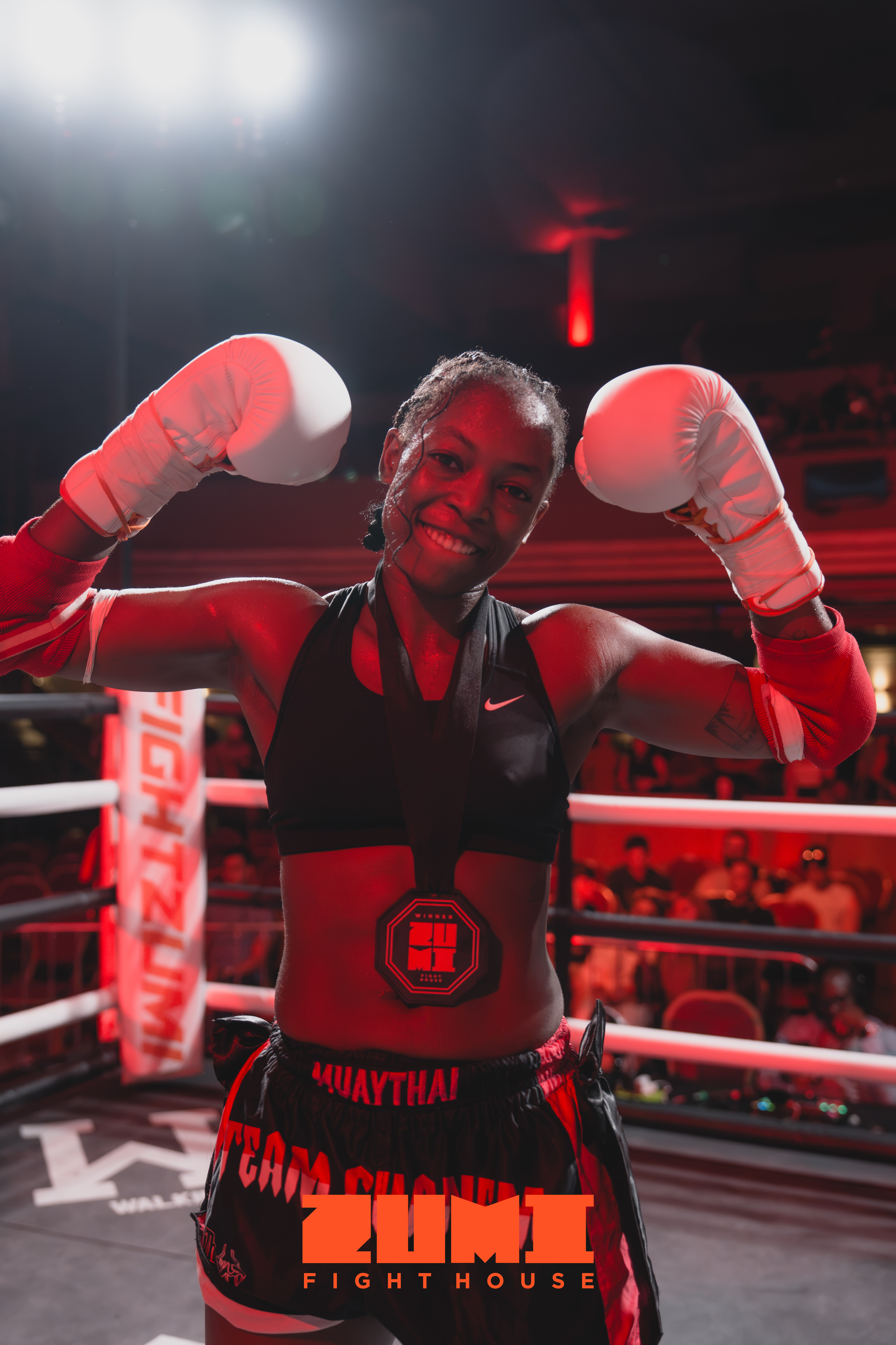 Zumi Fight House Muay Thai fighter posing with gloves raised in the ring